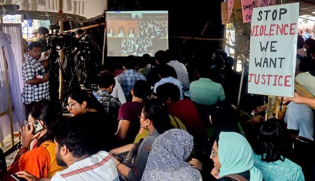 Students of RG Kar Medical College watch Supreme Court hearing on their protest site. PTI