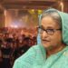 Sheikh Hasina. In the background is a video screengrab showing protesters in Bangladesh.