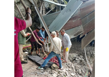 Body of female pilgrim being retrieved from damaged iron structure following landslide.