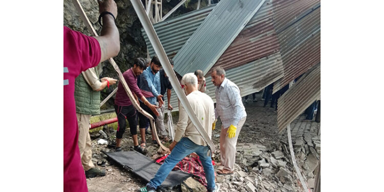 Body of female pilgrim being retrieved from damaged iron structure following landslide.