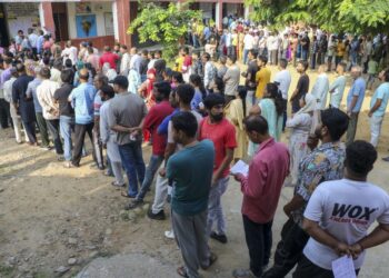 People wait in queues to cast their votes at a polling booth during the third and final phase of Jammu and Kashmir Assembly elections, in Jammu