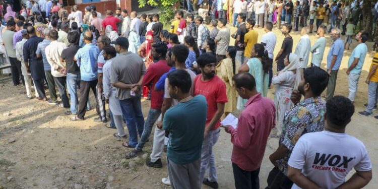 People wait in queues to cast their votes at a polling booth during the third and final phase of Jammu and Kashmir Assembly elections, in Jammu