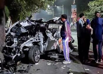 People gather around the car that got mangled after it got hit by a container, in Dehradun on Monday. At least six people were killed and one other was injured in the accident.