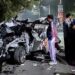 People gather around the car that got mangled after it got hit by a container, in Dehradun on Monday. At least six people were killed and one other was injured in the accident.