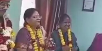 Both the husband and wife (second and second L) were seen wearing garlands and smiling during his farewell at office.