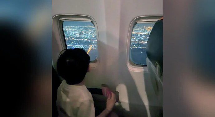 Photo posted by Kang Ko shows his three-year-old son peering out of a plane window on their flight to Bangkok.